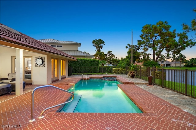 view of pool with a water view, a patio, and an in ground hot tub