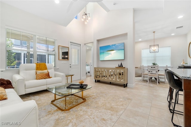 living room featuring light tile patterned floors, high vaulted ceiling, and an inviting chandelier