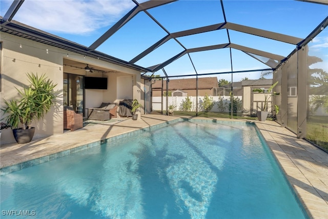 view of pool featuring glass enclosure, ceiling fan, and a patio