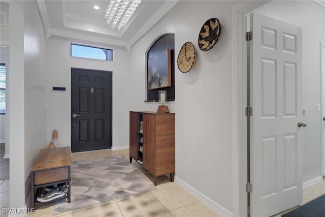 entryway featuring light tile patterned floors, an inviting chandelier, and ornamental molding