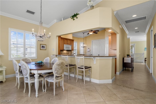 tiled dining area with ceiling fan with notable chandelier and crown molding