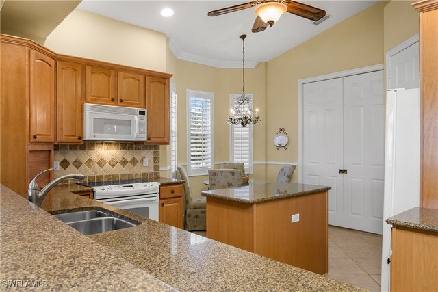 kitchen with backsplash, white appliances, sink, pendant lighting, and a center island