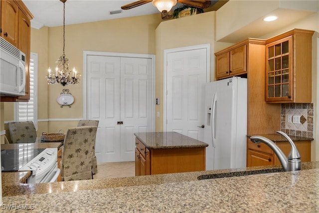 kitchen featuring white appliances, sink, a kitchen island, hanging light fixtures, and light tile patterned flooring