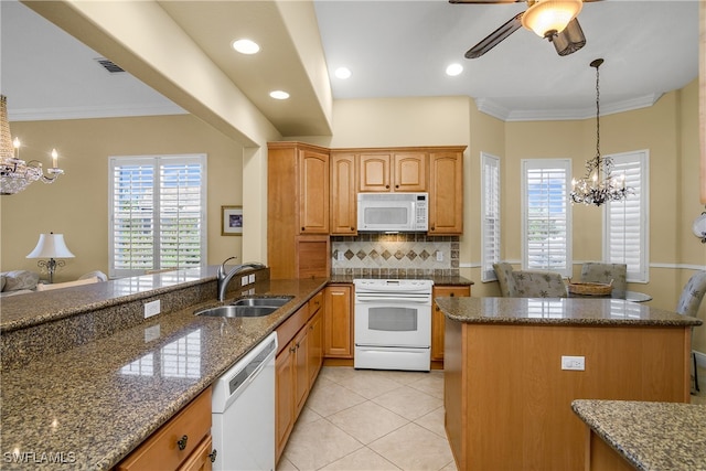 kitchen featuring white appliances, a wealth of natural light, dark stone countertops, and sink