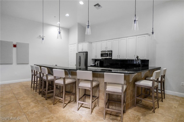 kitchen with a kitchen bar, white cabinetry, stainless steel appliances, and hanging light fixtures