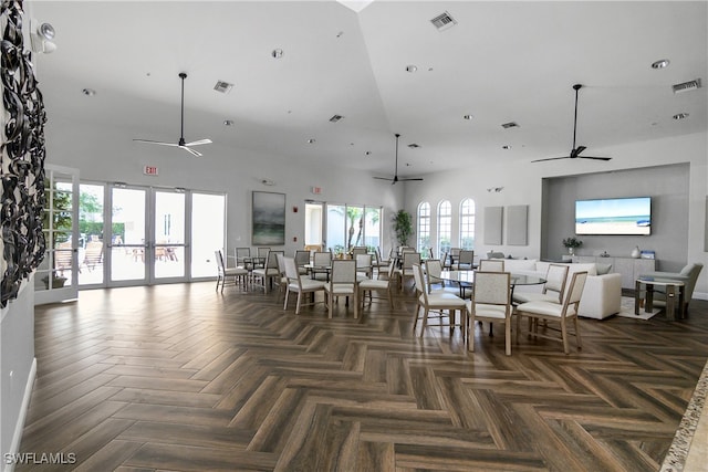 dining space featuring french doors, ceiling fan, dark parquet floors, and a high ceiling