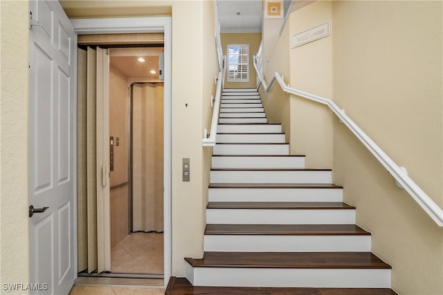 stairway with elevator and tile patterned flooring