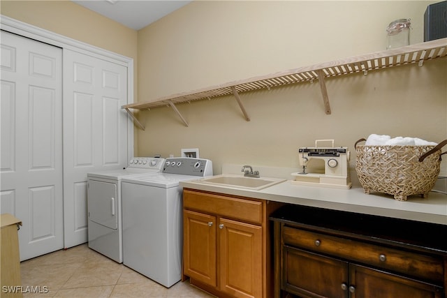 clothes washing area featuring washing machine and clothes dryer, light tile patterned floors, cabinets, and sink