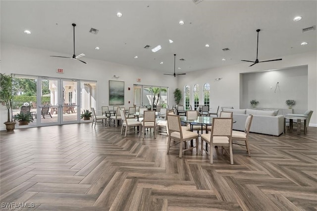 dining area featuring parquet floors, french doors, a towering ceiling, and a wealth of natural light