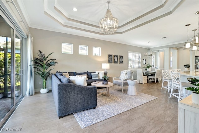 living room with a notable chandelier, ornamental molding, and a tray ceiling