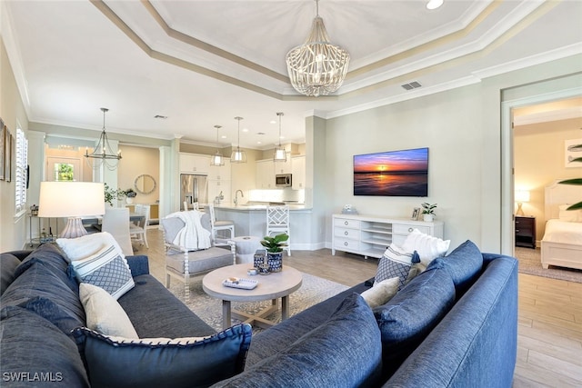 living room featuring ornamental molding, light hardwood / wood-style flooring, and a chandelier