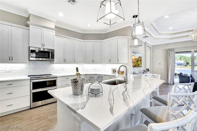 kitchen featuring pendant lighting, a breakfast bar, white cabinets, sink, and stainless steel appliances