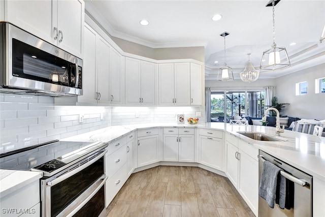 kitchen with decorative backsplash, appliances with stainless steel finishes, sink, pendant lighting, and white cabinetry