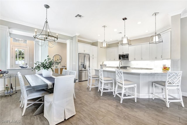 dining room featuring sink, ornamental molding, and an inviting chandelier