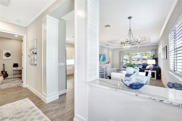 interior space with a raised ceiling, ornamental molding, and a notable chandelier