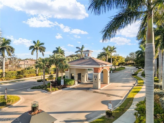 view of road featuring curbs, a gated entry, and sidewalks