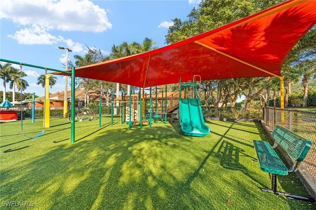 communal playground featuring fence and a lawn