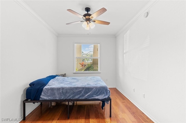 bedroom with light wood-style flooring, ornamental molding, ceiling fan, and baseboards