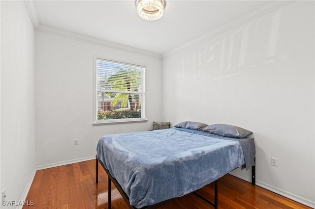 bedroom with baseboards, wood finished floors, and crown molding