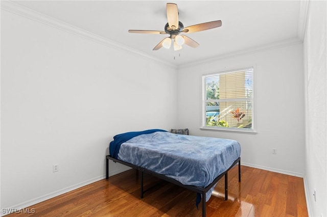 bedroom with a ceiling fan, baseboards, ornamental molding, and wood finished floors