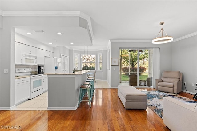 kitchen featuring white appliances, white cabinets, open floor plan, light wood-style floors, and crown molding