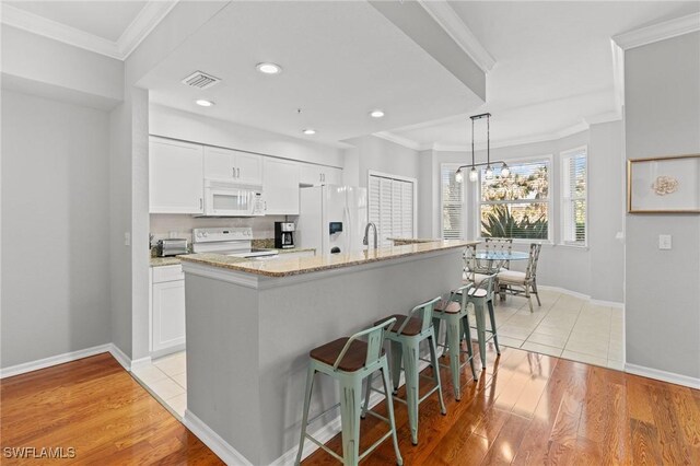 kitchen featuring ornamental molding, white appliances, a breakfast bar area, and visible vents