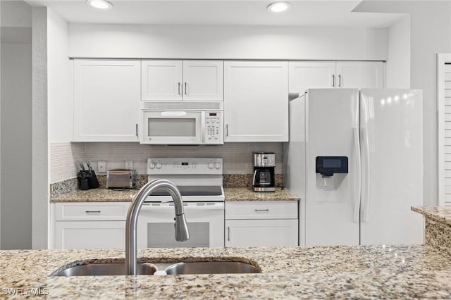 kitchen featuring white appliances, white cabinetry, backsplash, and a sink