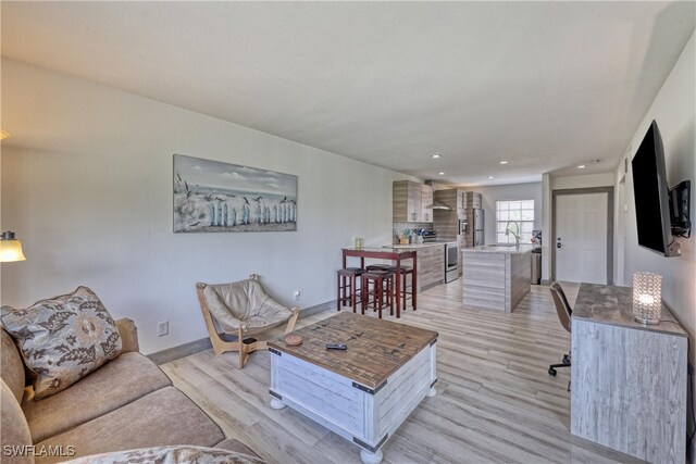 living room featuring sink and light hardwood / wood-style flooring