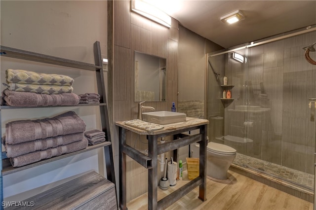 bathroom with hardwood / wood-style flooring, toilet, walk in shower, and sink