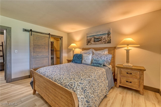 bedroom with a barn door and light hardwood / wood-style flooring