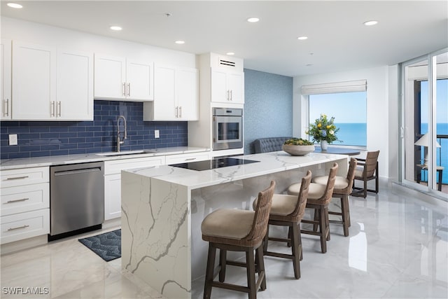 kitchen featuring white cabinets, a water view, sink, a kitchen island, and stainless steel appliances