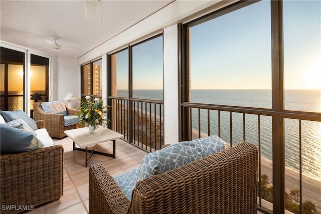 sunroom / solarium featuring ceiling fan and a water view