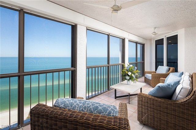 sunroom featuring ceiling fan and a water view