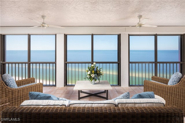 sunroom with ceiling fan and a water view