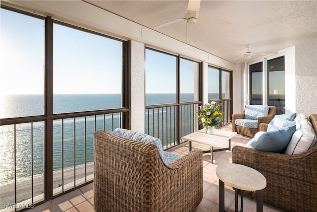 sunroom featuring ceiling fan, a healthy amount of sunlight, and a water view