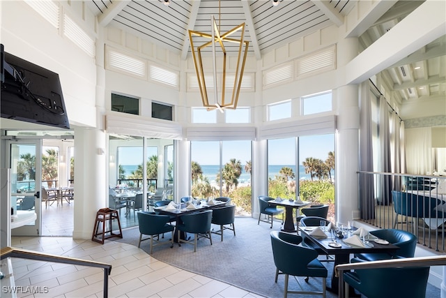 sunroom with a chandelier, french doors, lofted ceiling with beams, and a water view