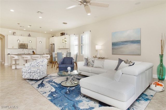 living room with light tile patterned floors, ceiling fan, and sink