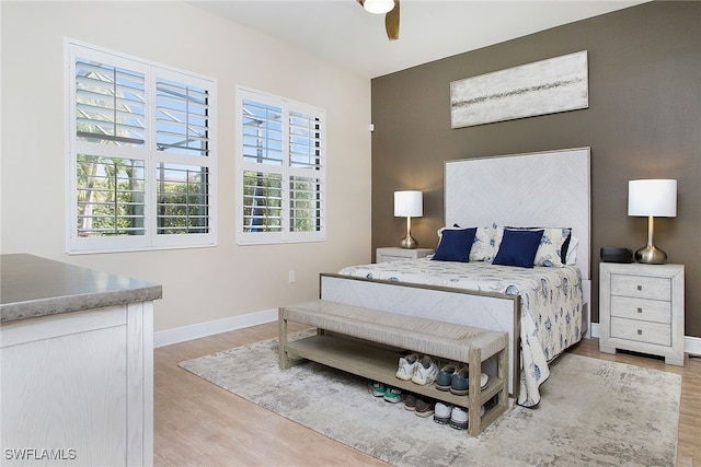 bedroom with ceiling fan, light hardwood / wood-style floors, and multiple windows