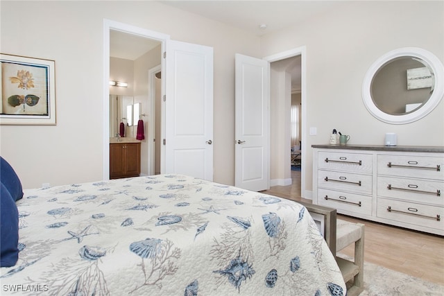 bedroom featuring light wood-type flooring and ensuite bathroom