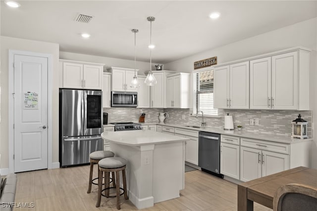 kitchen with white cabinetry, sink, a center island, pendant lighting, and appliances with stainless steel finishes