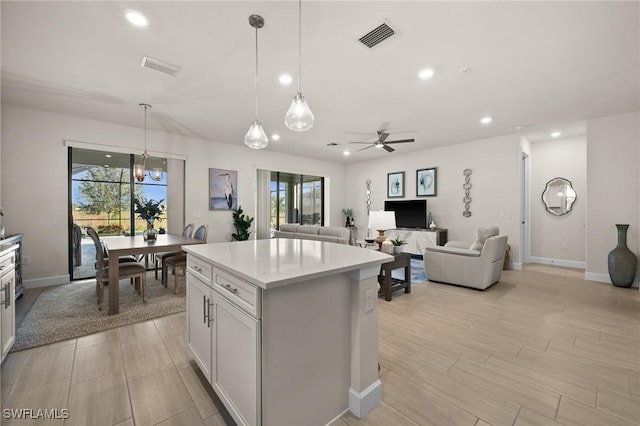 kitchen with ceiling fan, a center island, white cabinets, and pendant lighting