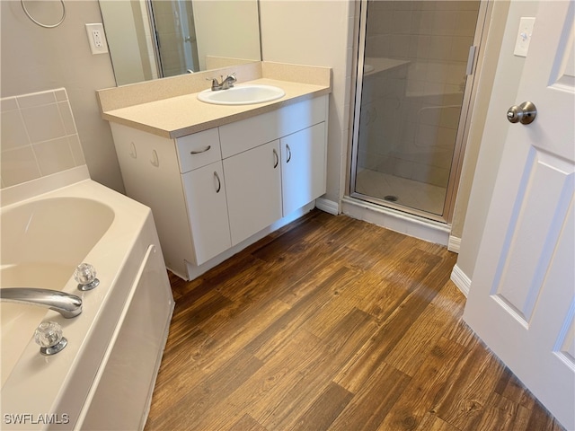 bathroom featuring hardwood / wood-style floors, vanity, and plus walk in shower