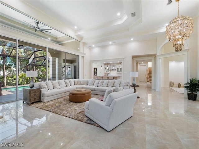 living room featuring ceiling fan with notable chandelier, crown molding, and a high ceiling