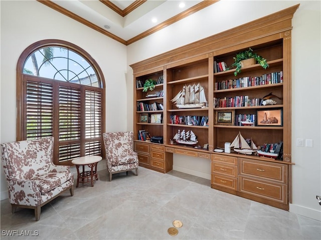 living area with built in desk and ornamental molding