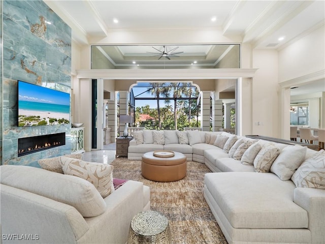 living room featuring ceiling fan, a fireplace, plenty of natural light, and ornamental molding