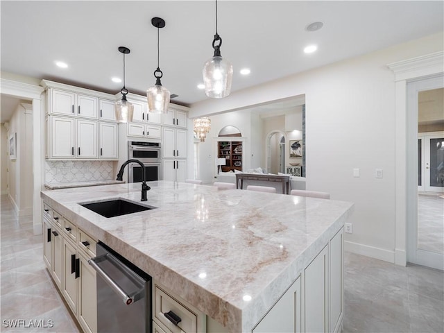 kitchen featuring a large island with sink, tasteful backsplash, pendant lighting, and sink