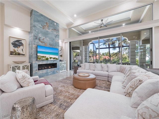 living room featuring ceiling fan, crown molding, and a high end fireplace