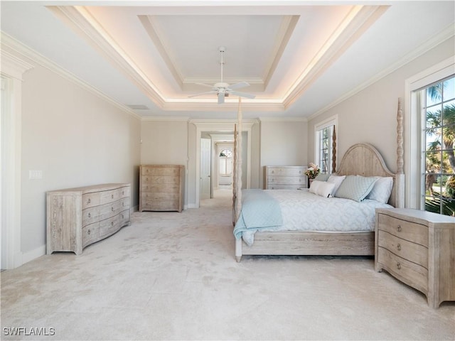 carpeted bedroom with a tray ceiling, ceiling fan, and crown molding