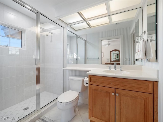 bathroom featuring vanity, a shower with door, tile patterned floors, ceiling fan, and toilet