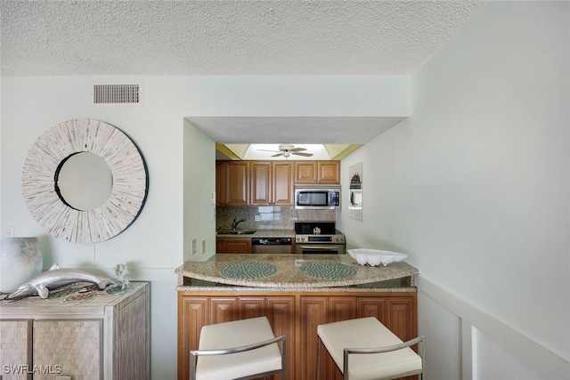 kitchen featuring appliances with stainless steel finishes, tasteful backsplash, a textured ceiling, ceiling fan, and sink